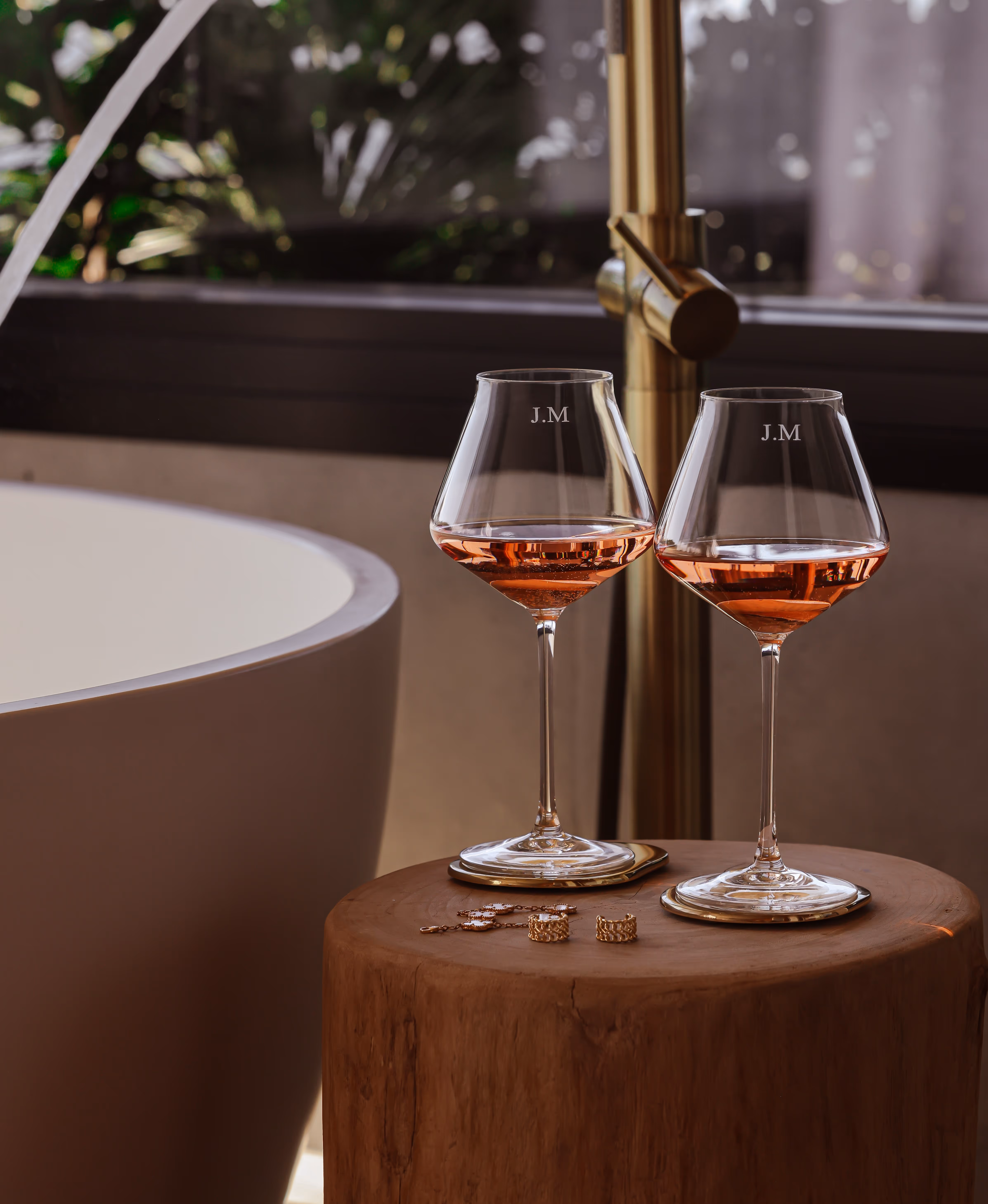Two wine glasses on a timber side table beside a stone bath, shot for Mont Laurent